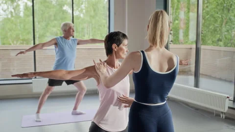 Yoga Instructor Adjusting Poses of Senior and Middle Aged Students Stock Footage 339866561