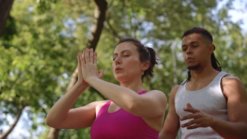 Yoga instructor assists participant with posture correction during outdoor class Stock Footage 302115969