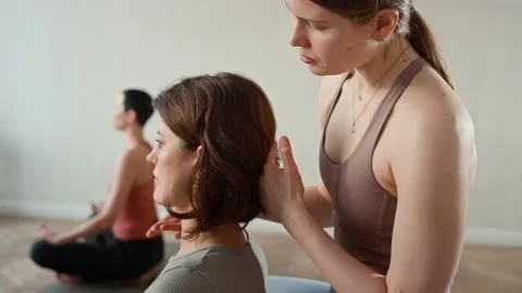 Yoga Instructor Correcting Posture of Woman in Lotus Position Stock Footage 329680663