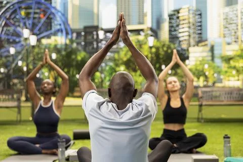 Yoga instructor demonstrating raised arms stretch as women participants follow Stock Photos