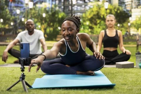 Yoga instructor leaning on mat to adjust smartphone and record fitness routine Stock Photos