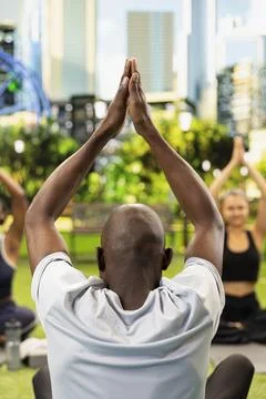 Yoga instructor seen from behind guides participants through meditation Stock Photos