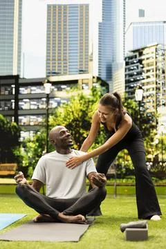 Yoga instructor smiling while giving hands-on chest and shoulder guidance Stock Photos