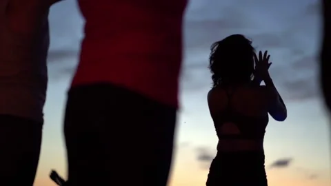 Yoga instructor teaches class in silhouette at dusk Vídeo Stock 138592228