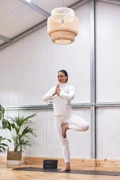 Yoga instructor teaching a complicated posture in a well-decorated indoor gym Stock Photos