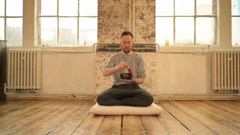 Yoga instructor using Tibetan singing bowl in yoga class Stock Footage 112999599
