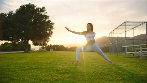 Yoga master doing yoga session at park, backlit sunlight Stock Footage 129999213