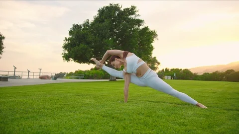 Yoga master doing yoga session at park, backlit sunlight Stock Footage 129999331