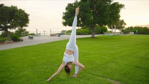 Yoga master doing yoga session at park, backlit sunlight Stock Footage 129999334
