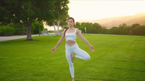 Yoga master doing yoga session at park, backlit sunlight Stock Footage 129999341