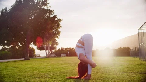 Yoga master doing yoga session at park, backlit sunlight Stock Footage 130049979