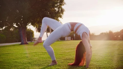 Yoga master doing yoga session at park, backlit sunlight Stock Footage 130050140
