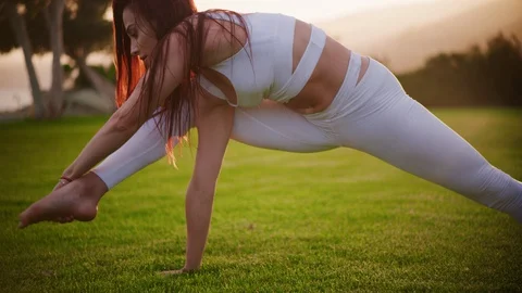 Yoga master doing yoga session at park, backlit sunlight Stock Footage 130050515