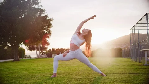 Yoga master doing yoga session at park, backlit sunlight Stock Footage 130050562