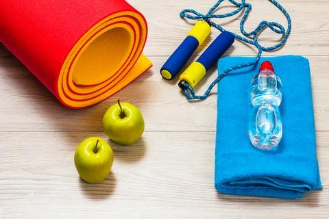 Yoga mat and different tools for fitness on floor in room. Stock Photos