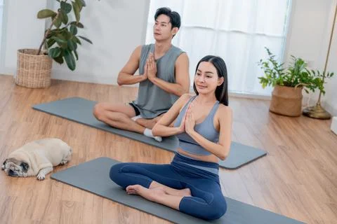 Yoga practice in a home studio with two people and a pug dog during a calmi.. Stock Photos