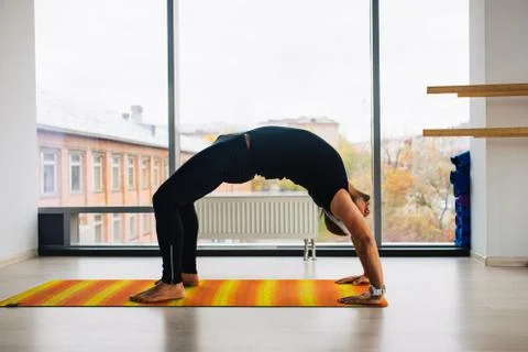 Yoga practice. Man doing bridge pose inside room with panoramic windows Foto stock