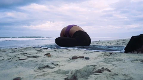 Yoga practice  at a stone beach facing the ocean - young woman Stock Footage 99048620