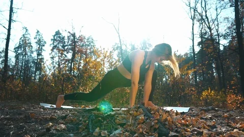 Yoga practitioner does adho mukha shvanasana in forest Stock Footage 125070463