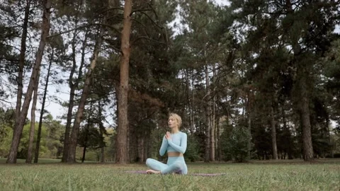 A yoga practitioner does exercises during the day in an outdoor park Stock Footage 149902223