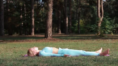 A yoga practitioner does exercises during the day in an outdoor park Stock Footage 149902319