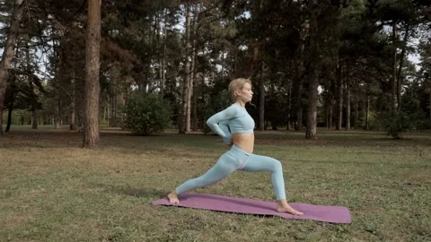 A yoga practitioner does exercises during the day in an outdoor park Stock Footage 149902352