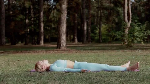 A yoga practitioner does exercises during the day in an outdoor park Stock Footage 149902400