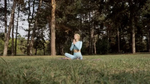 A yoga practitioner does exercises during the day in an outdoor park Stock Footage 149902413