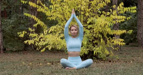 A yoga practitioner does exercises during the day in an outdoor park Stock Footage 149902487