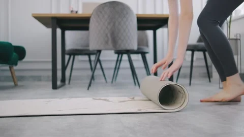 Yoga practitioner prepares to roll out mat in a modern living room during a Stock Footage 302660224