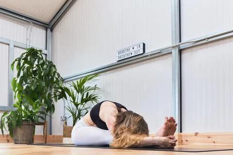Yoga stretch of a recognizable faceless Hispanic woman in a pretty studio Stock Photos