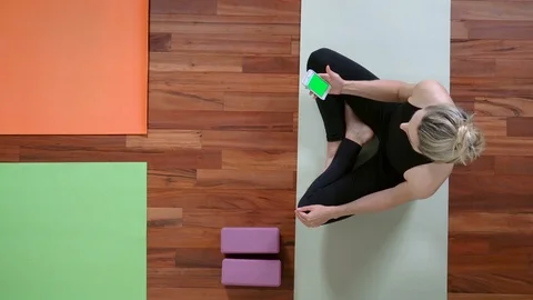 Yoga studio concept. Top view of woman sitting looking at Smartphone in her hand Vidéo 107951644