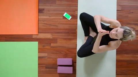Yoga studio concept. Top view of woman with Smartphone sitting raising up hands Stock Footage 107952837