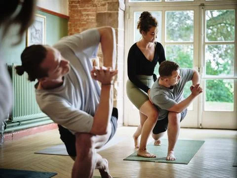 Yoga studio, instructor help student and stretch in class, woman and exercise Stock Photos