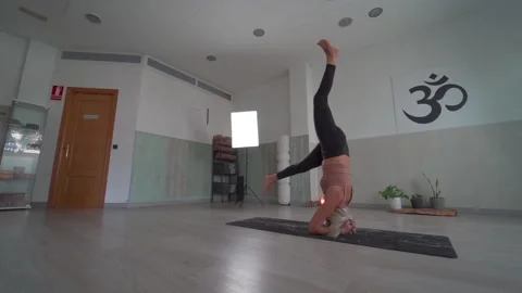 Yoga teacher doing the exercise of head stand yoga pose with variations in a  Stock Footage 146605436