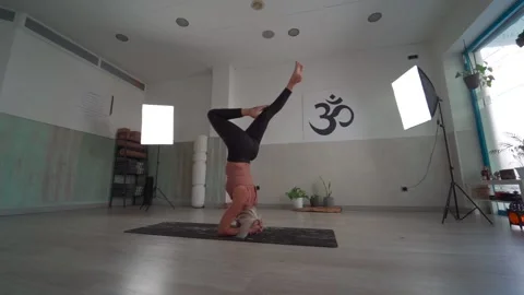 Yoga teacher doing the exercise of head stand yoga pose with variations in a  Video stock 146605437