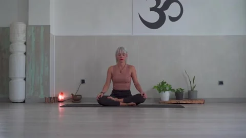 Yoga teacher doing relaxation exercise on a mat with her legs crossed. Woman  Video stock 146605547