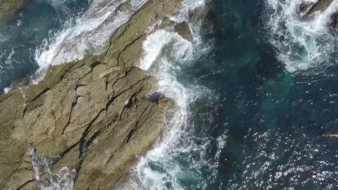 Yoga teacher doing yoga on the cliffs in the sea. Aerial drone view. Stock Footage 73685022