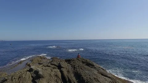Yoga teacher doing yoga on the cliffs in the sea. Aerial drone view. Stock Footage 73685155
