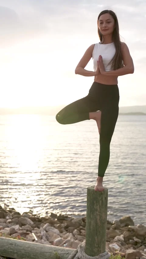 Yoga tree pose on a wooden post at sunset, Urla, Turkey - September 27, 2022 Stock Footage 327013949