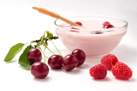 Yoghurt from a raspberry and a cherry in a glass bowl with a wooden spoon Stock Photos