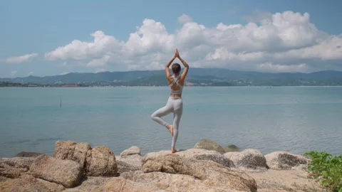 Yogi young girl practicing pose for balance exercising on beach in the morning Stock Footage 240540660