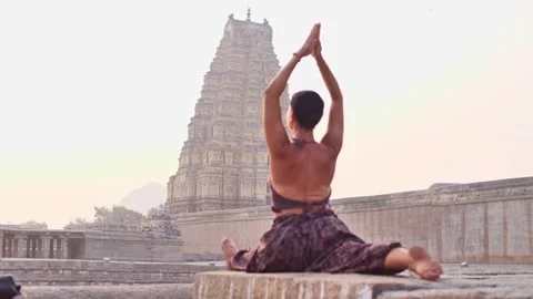 Yogini sits on the splits in front of the temple Stock Footage 264085220