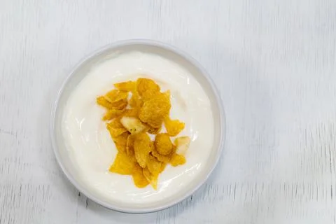 Yogurt in ceramic cup have corn flakes on white wood background. Stock Photos