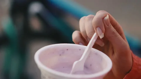 Yogurt. The girl eats a plastic spoon yogurt from a plastic cup. Stock Footage 111274870