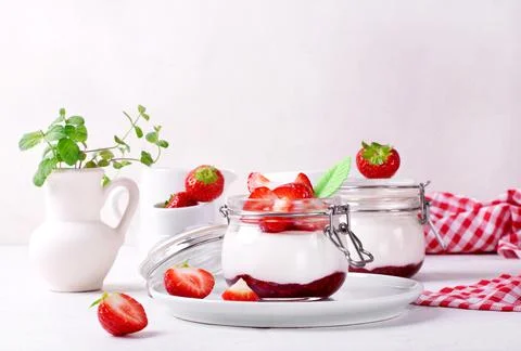 Yogurt with raspberry jam in the jar topped with strawberries Fotos Stock