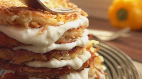 Yogurt is squeezed out by drops of them under the pyramids of potato pancakes Stock Footage 233181962