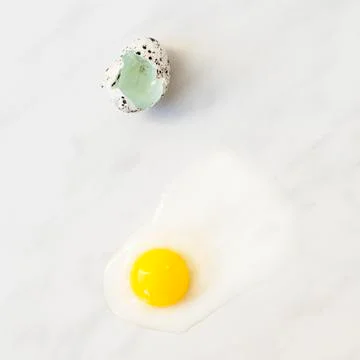 The yolk and the shell of quail eggs on a marble surface Stock Photos