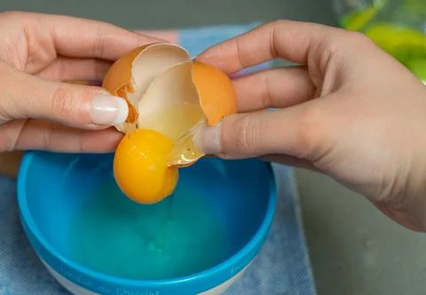 Yolk inside a broken egg falling in a bowl Stock Photos