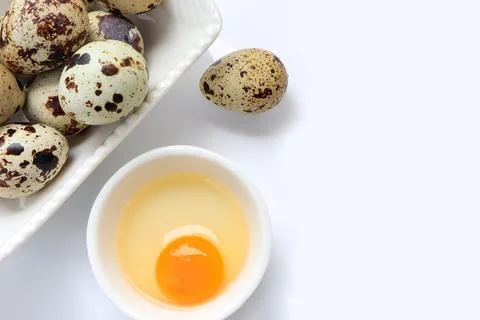Yolk quail egg without shell and raw quail eggs in bowl on white background. Stock Photos